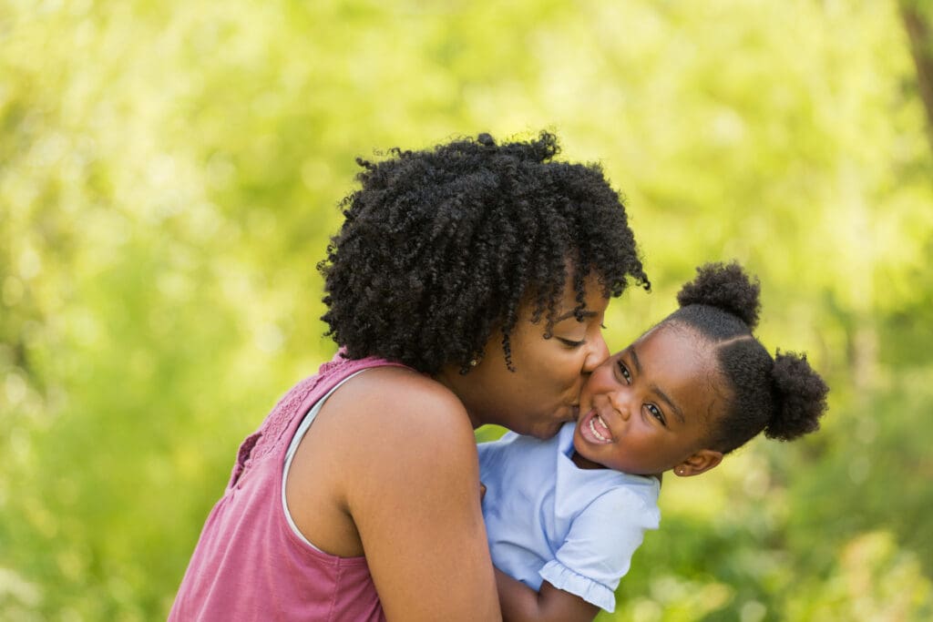 Mother and child laughing and embracing outdoors.