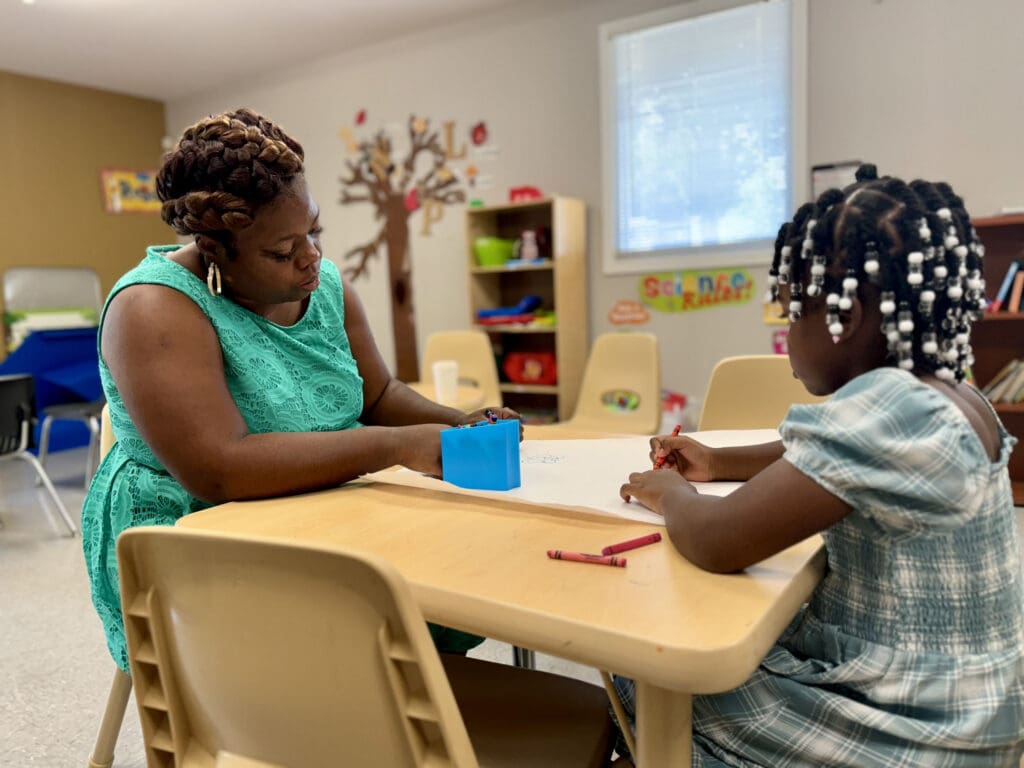 Mother in a green dress doing crafts at a table.