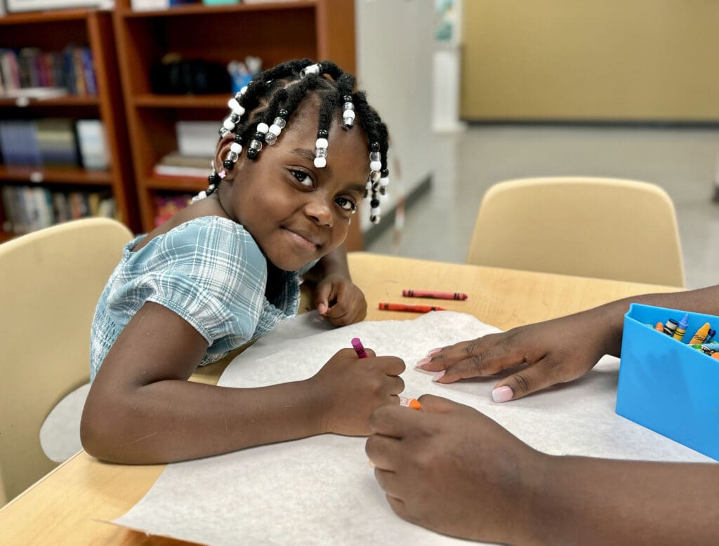 Child coloring and smiling.