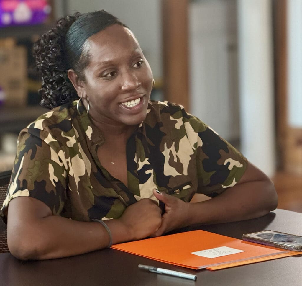 Woman sitting at a table smiling and conversing.