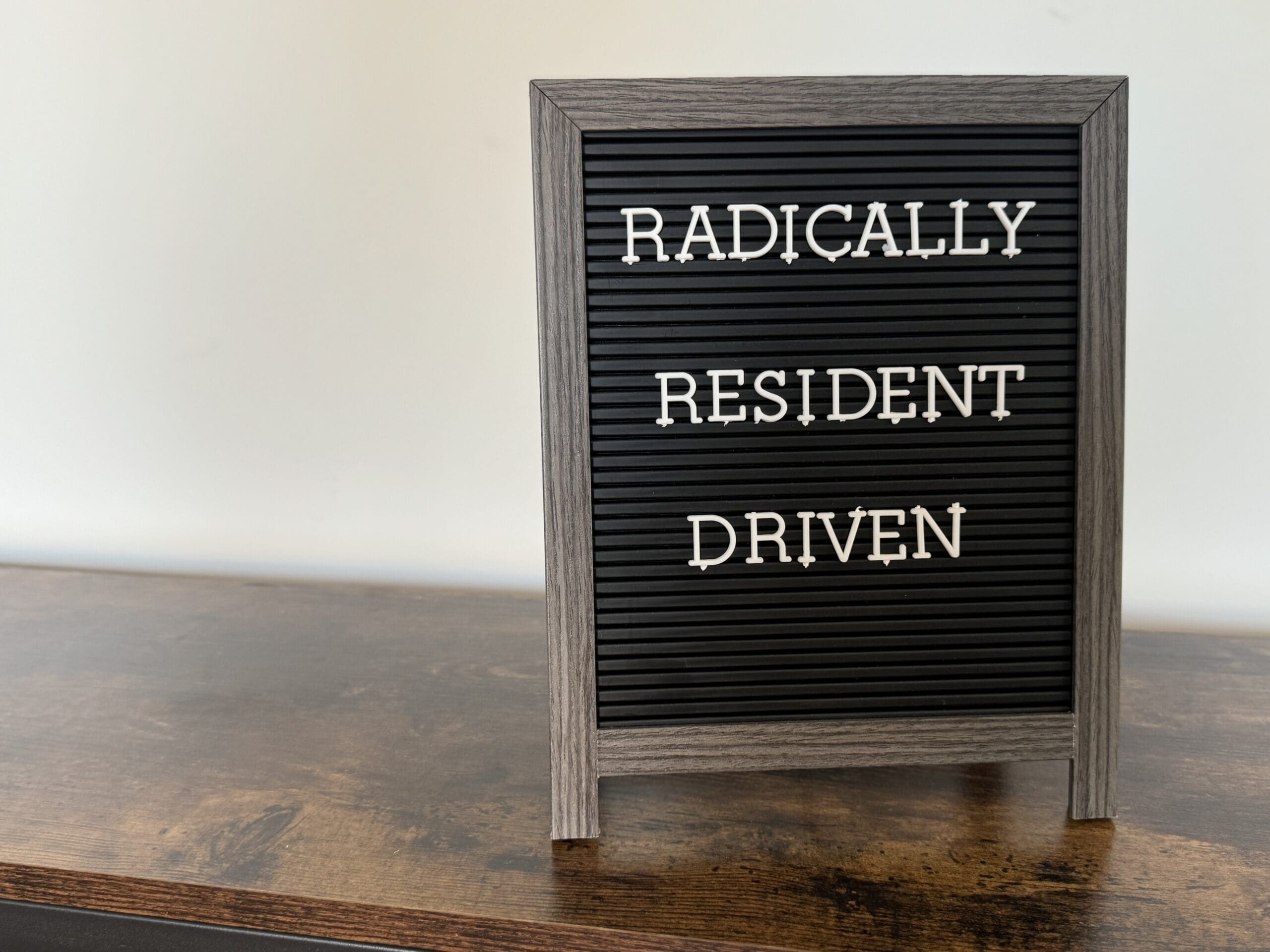 A sign sitting on a table that says "Radically Resident Driven"