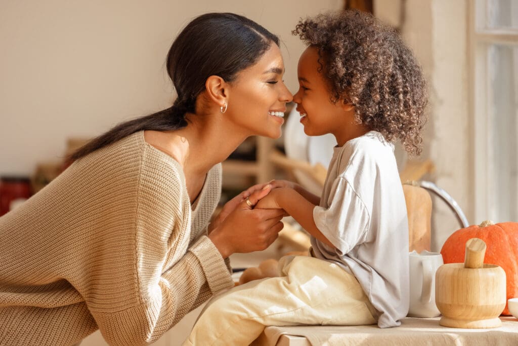 Mother and child laughing in a kitchen.